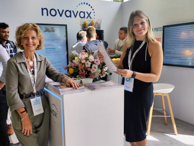 two people in front of a novavax sign